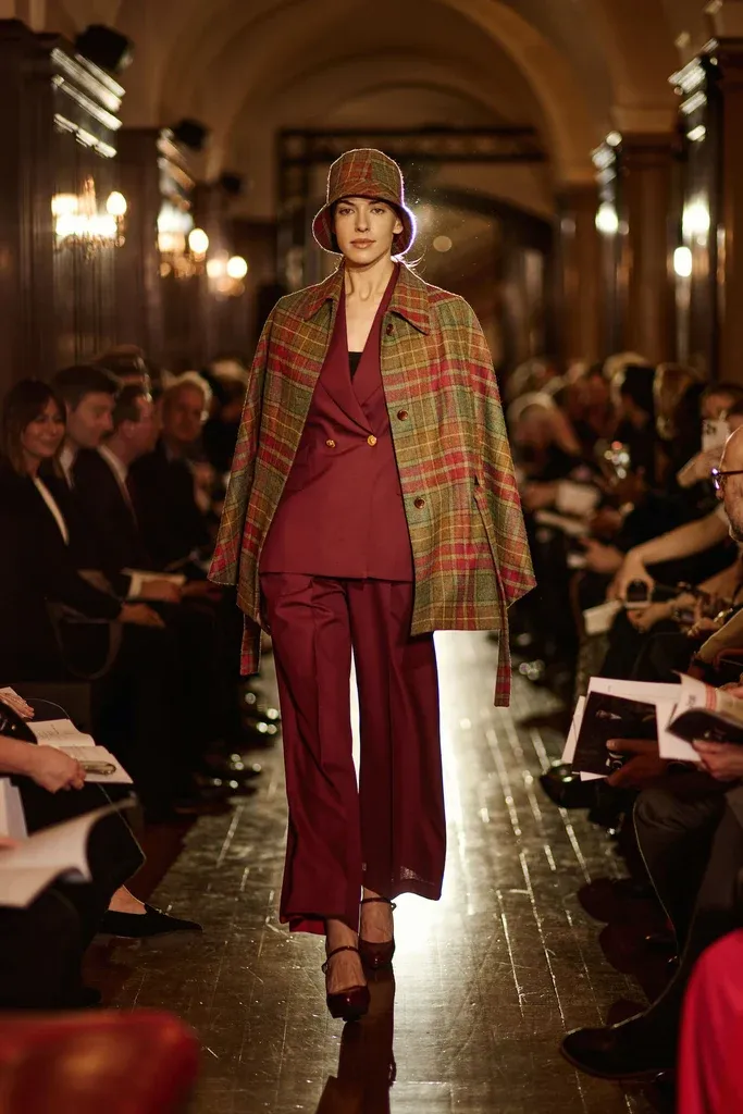 Plaid wool cape worn over a burgundy suit on the catwalk