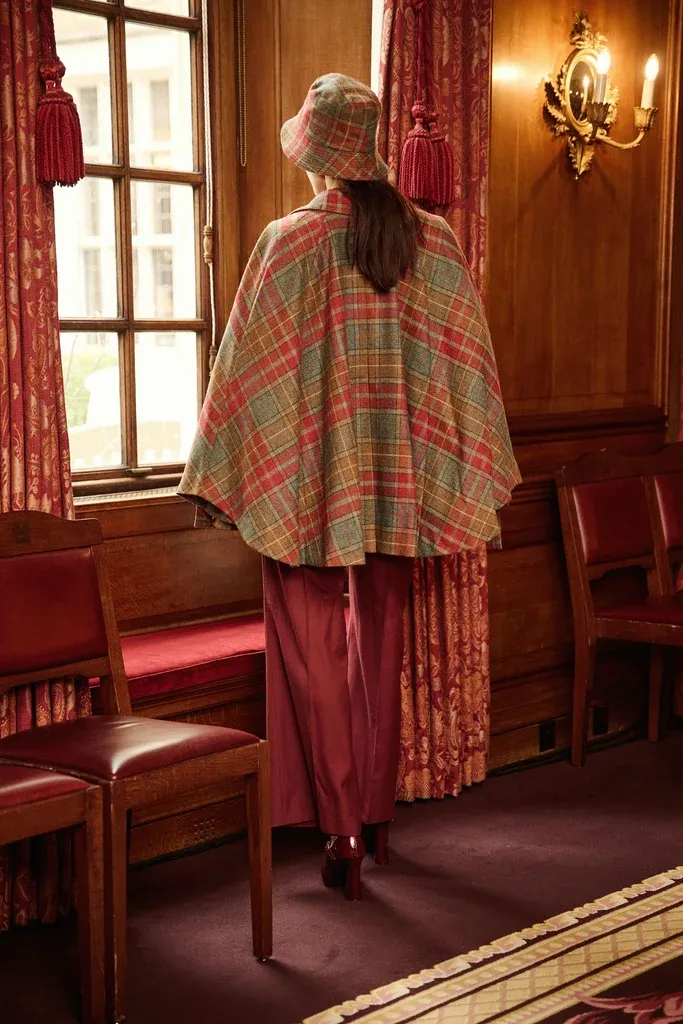 Rear view of a tailored plaid wool cape in a panelled interior
