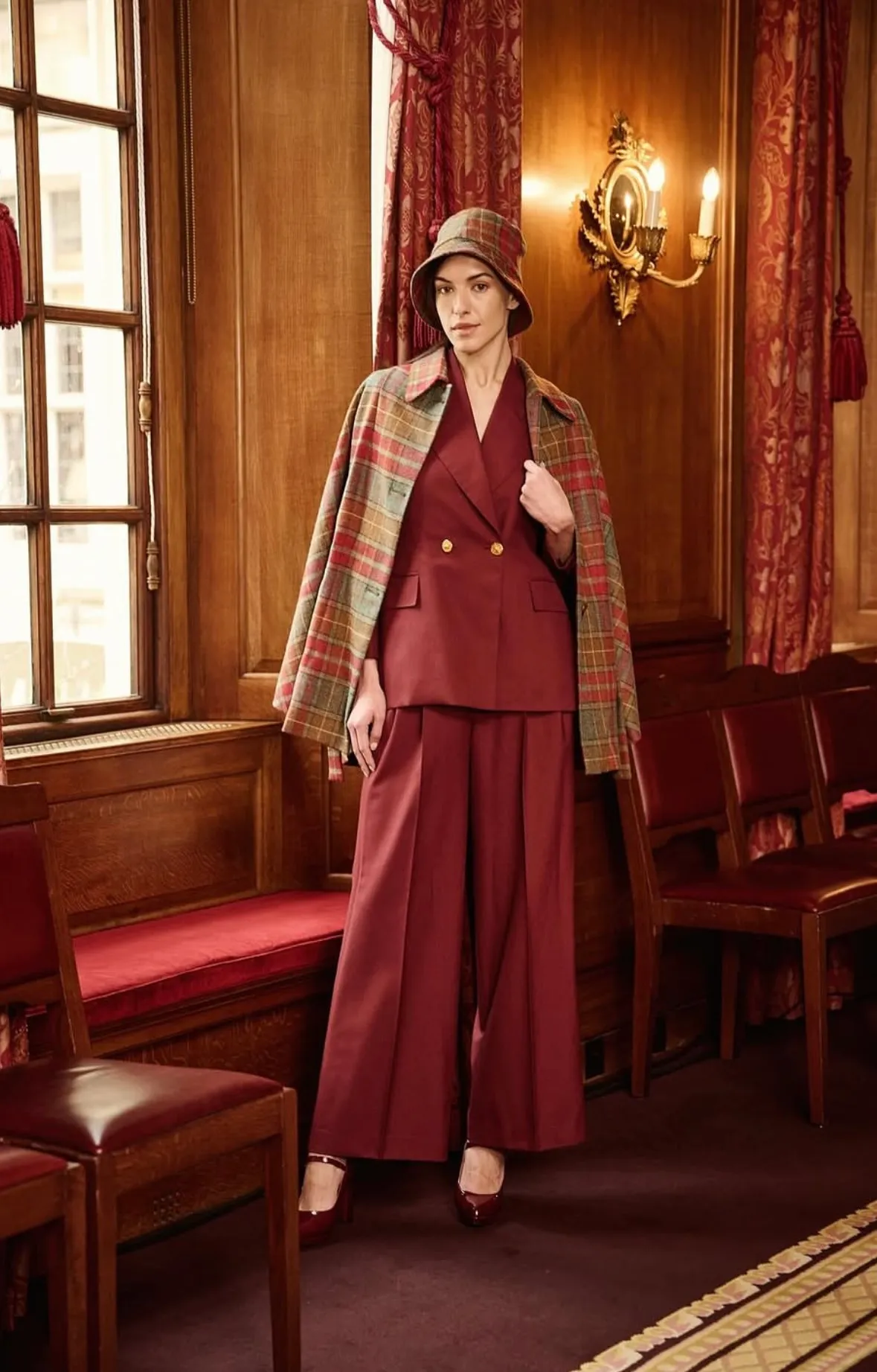 Plaid wool cape and burgundy tailored suit in a wood-panelled room