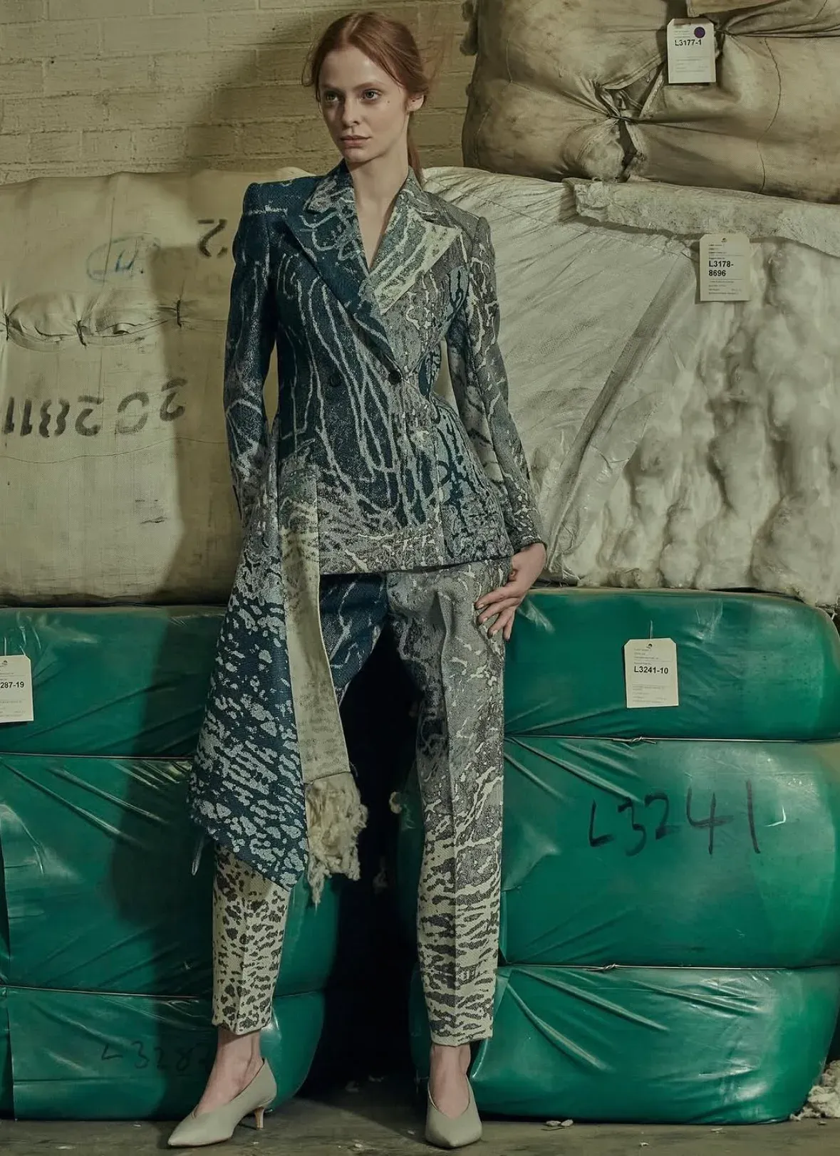 Full-length view of the blue jacquard tailored suit against wool bales