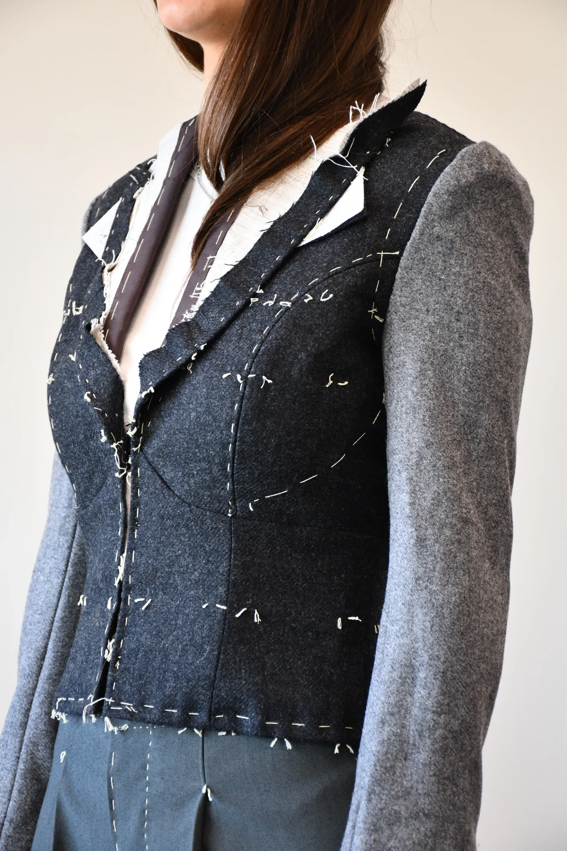 Close-up of hand-basted canvassing on a grey wool jacket shoulder, mid-construction