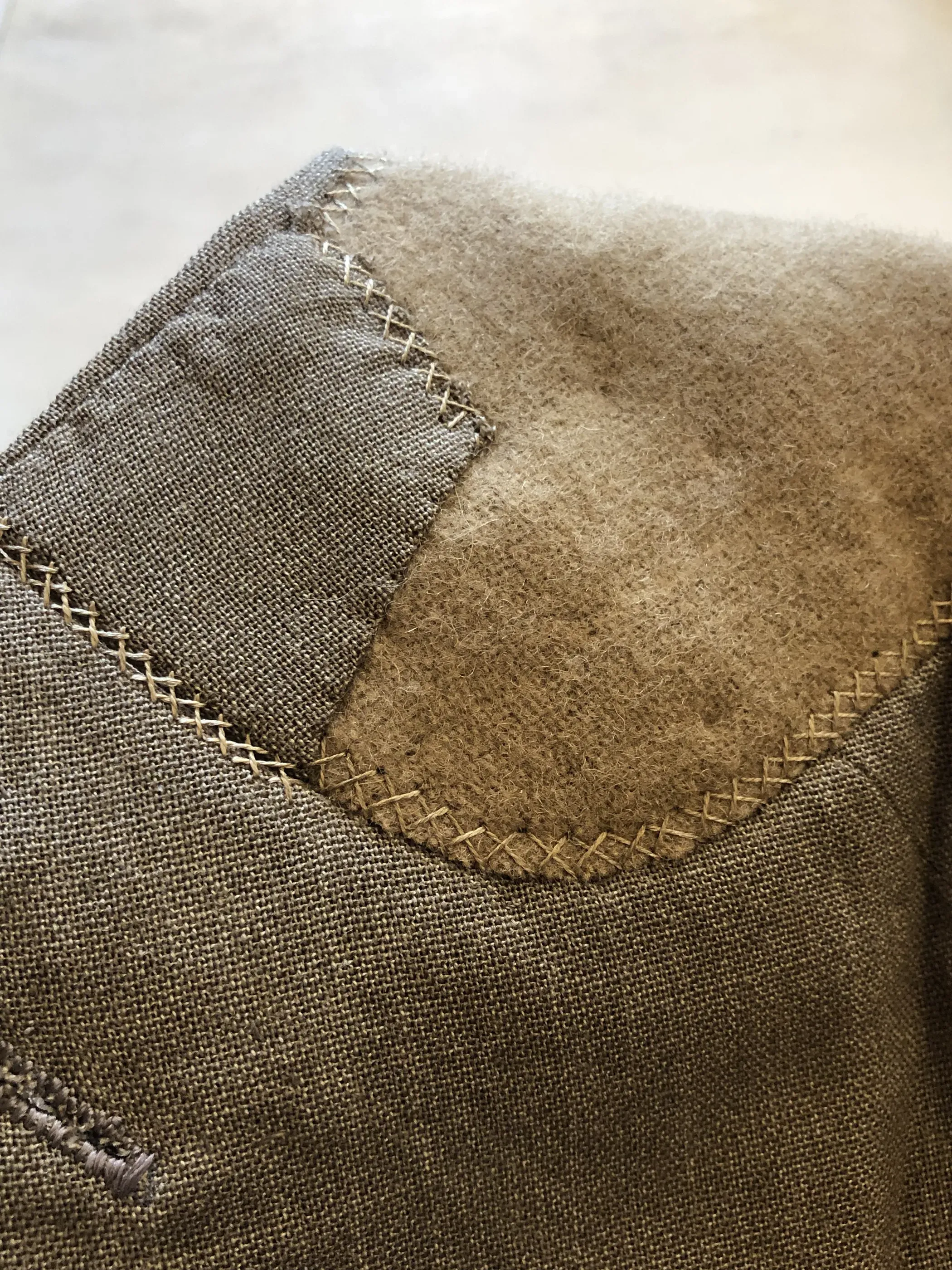 Macro detail of hand-finished zigzag stitching on a jacket seam